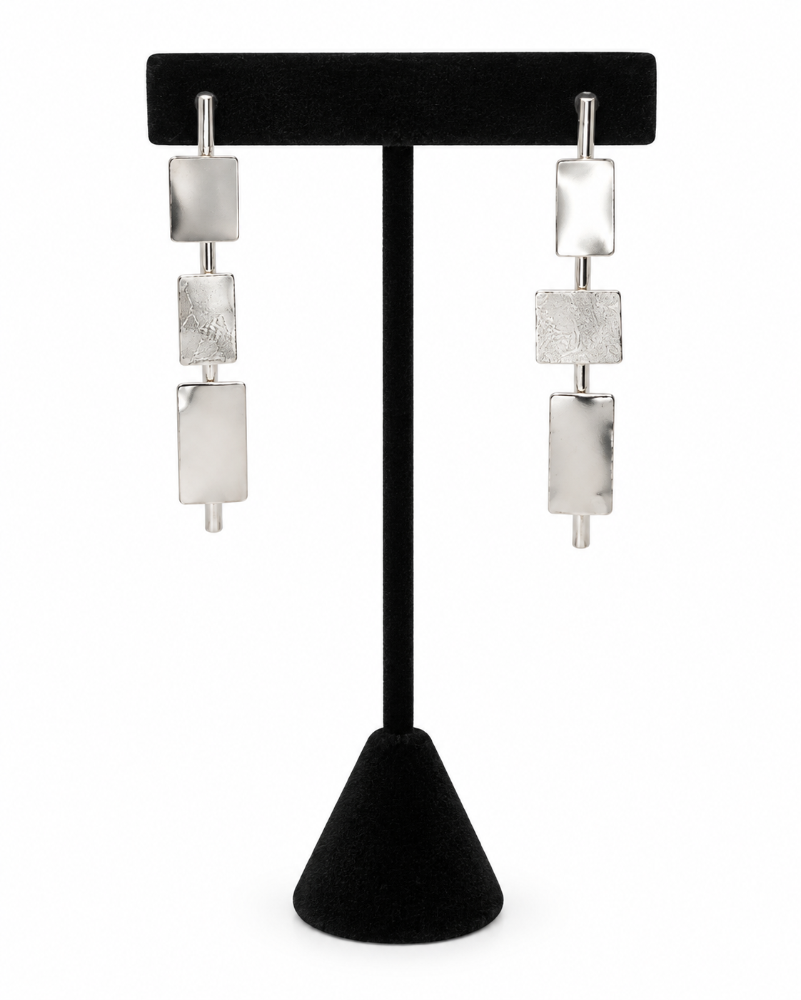 Clarity geometric sterling silver earrings featuring three rectangular metal elements arranged vertically on slim bars, displayed on a black jewelry stand.