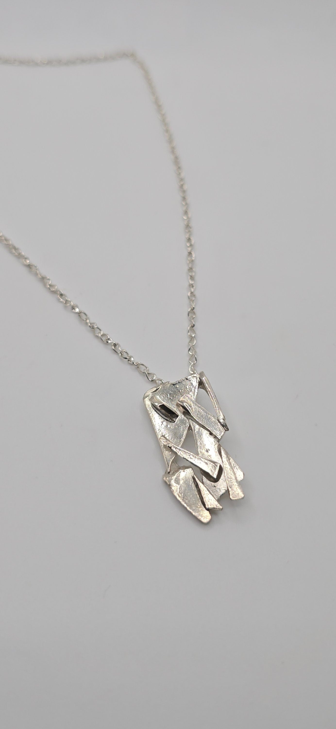 Made from shards of broken glass, this sterling silver pendant has a unique pattern. Comes on a 20" sterling chain. Made by Jill Melyssa
