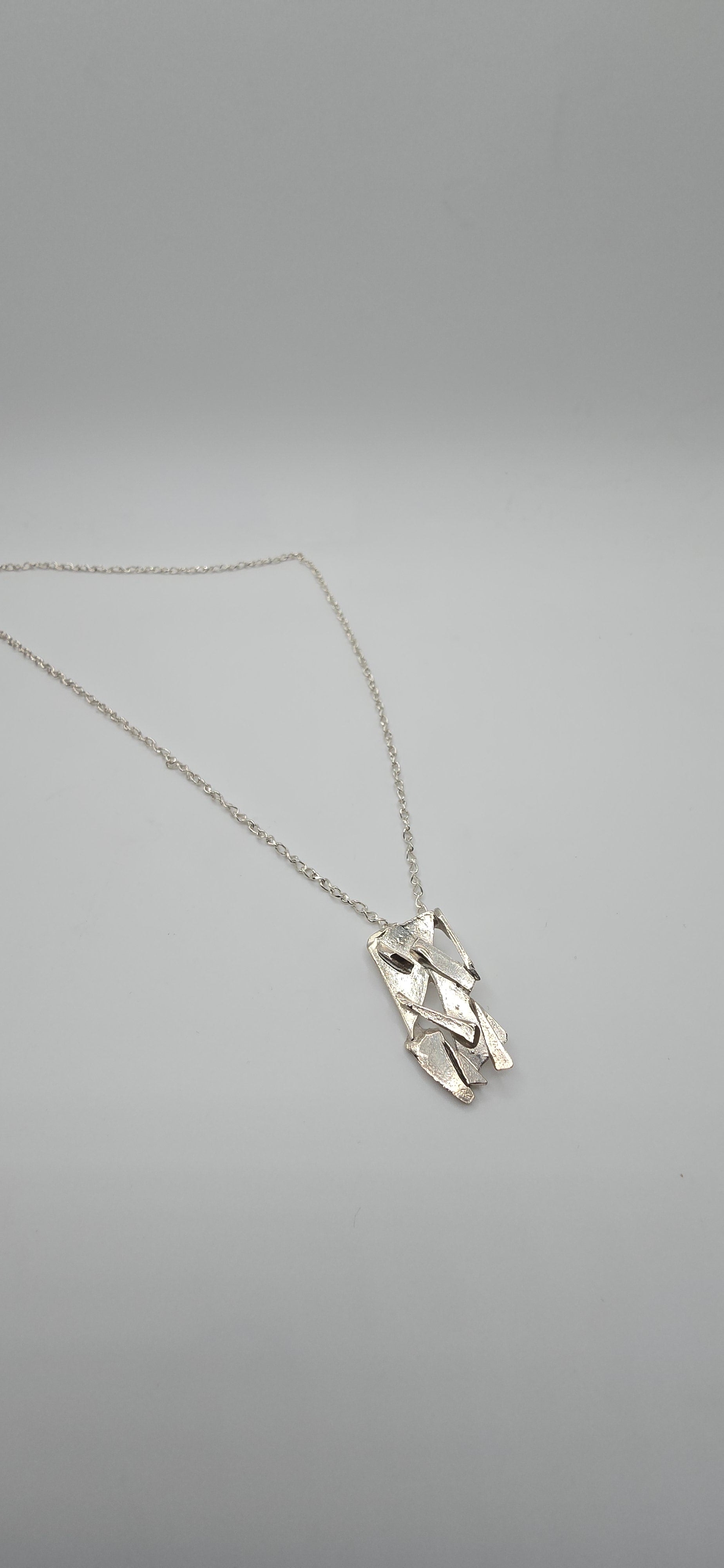 Made from shards of broken glass, this sterling silver pendant has a unique pattern. Comes on a 20" sterling chain. Made by Jill Melyssa