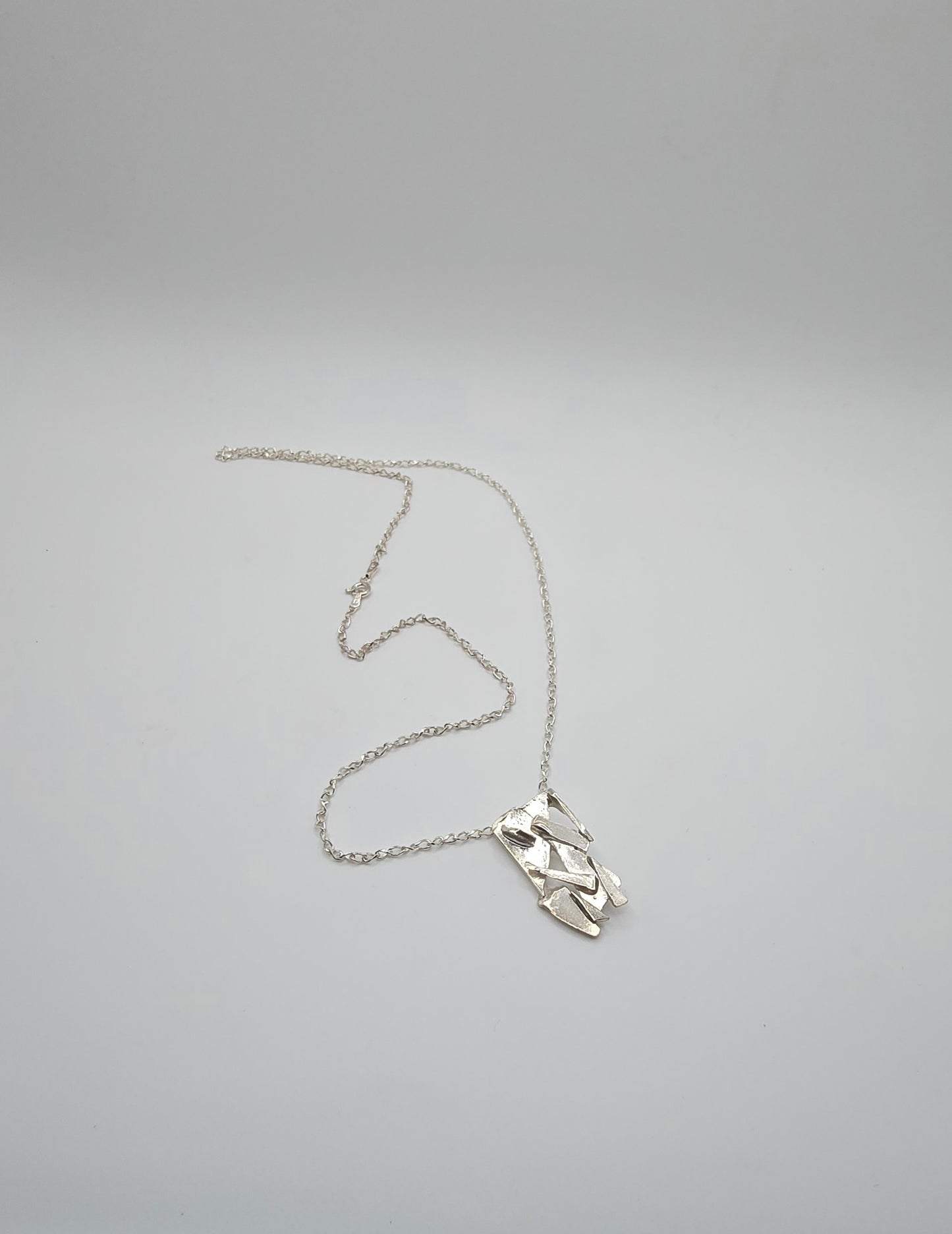 Made from shards of broken glass, this sterling silver pendant has a unique pattern. Comes on a 20" sterling chain. Made by Jill Melyssa