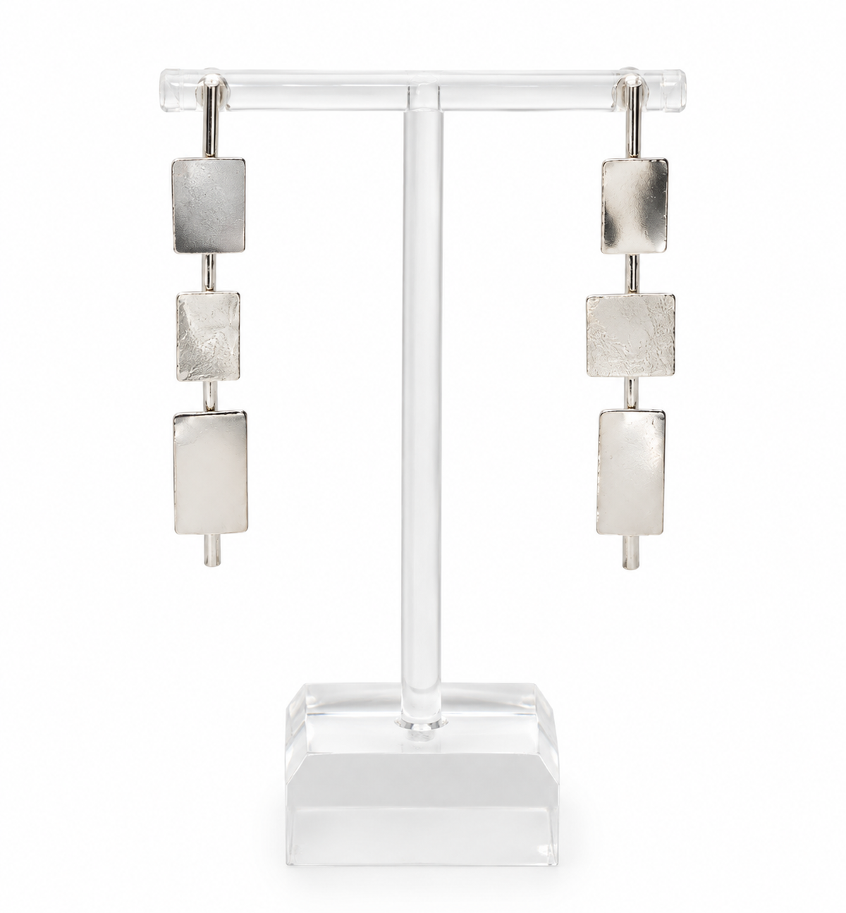 Clarity sterling silver earrings with three geometric rectangular elements in varied textures and finishes, displayed on a clear acrylic jewelry stand.