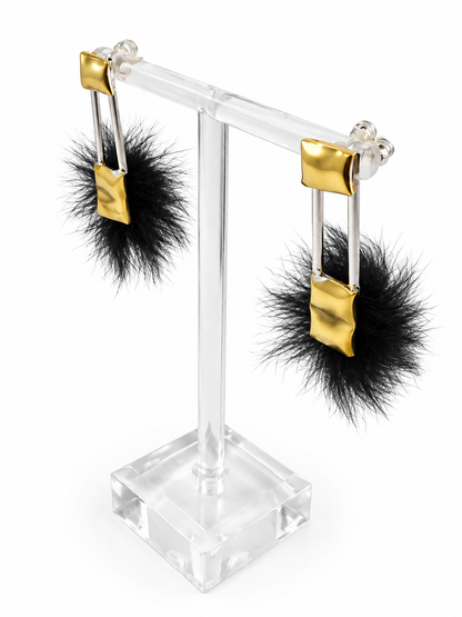 Close up of Comfort & Void earrings showing the rounded, dimensional brass forms, soft faux fur, and open spaces between the sculptural elements.