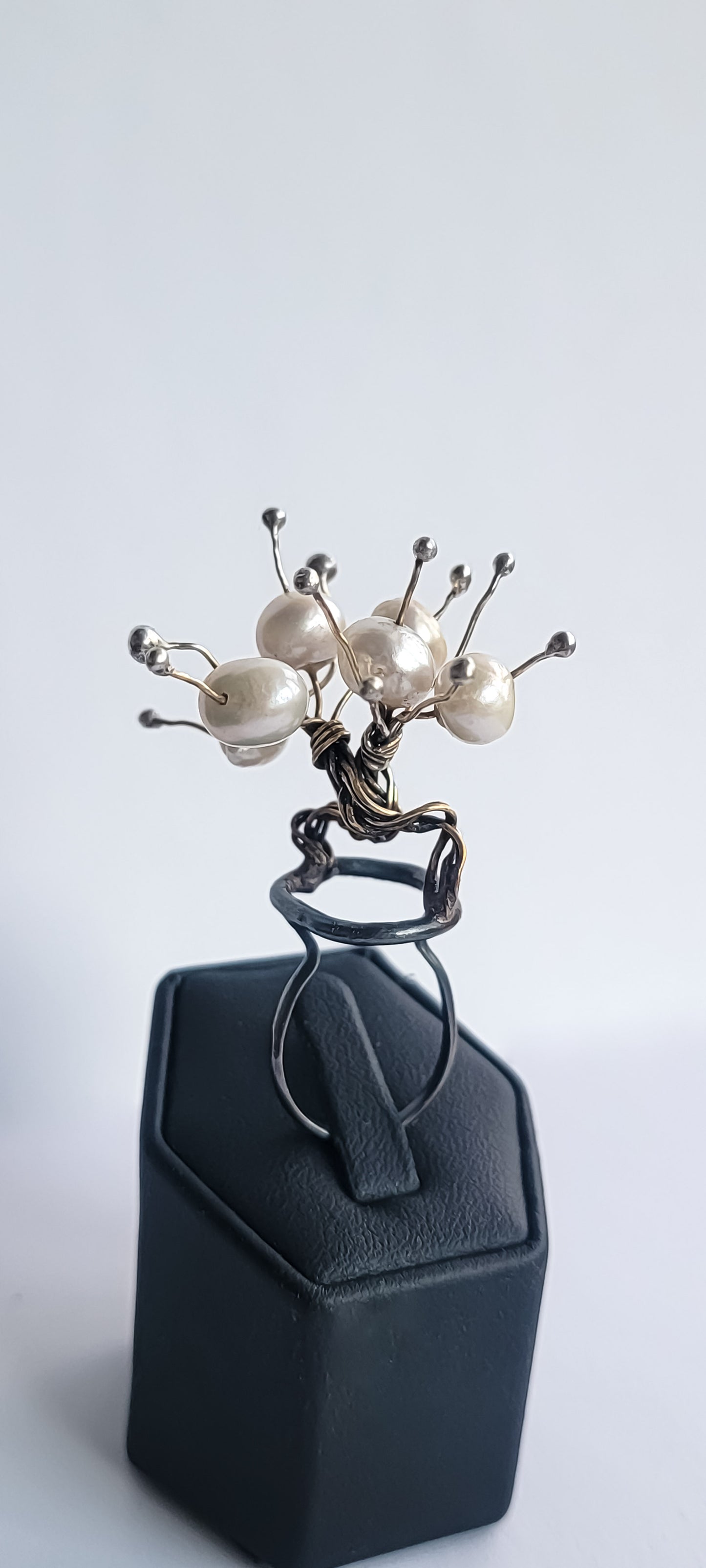Jeweler's brass and sterling silver statement ring. Two braided trees are intertwined in a hugging position with white freshwater pearls on the top and sterling balls on the ends of each wire.