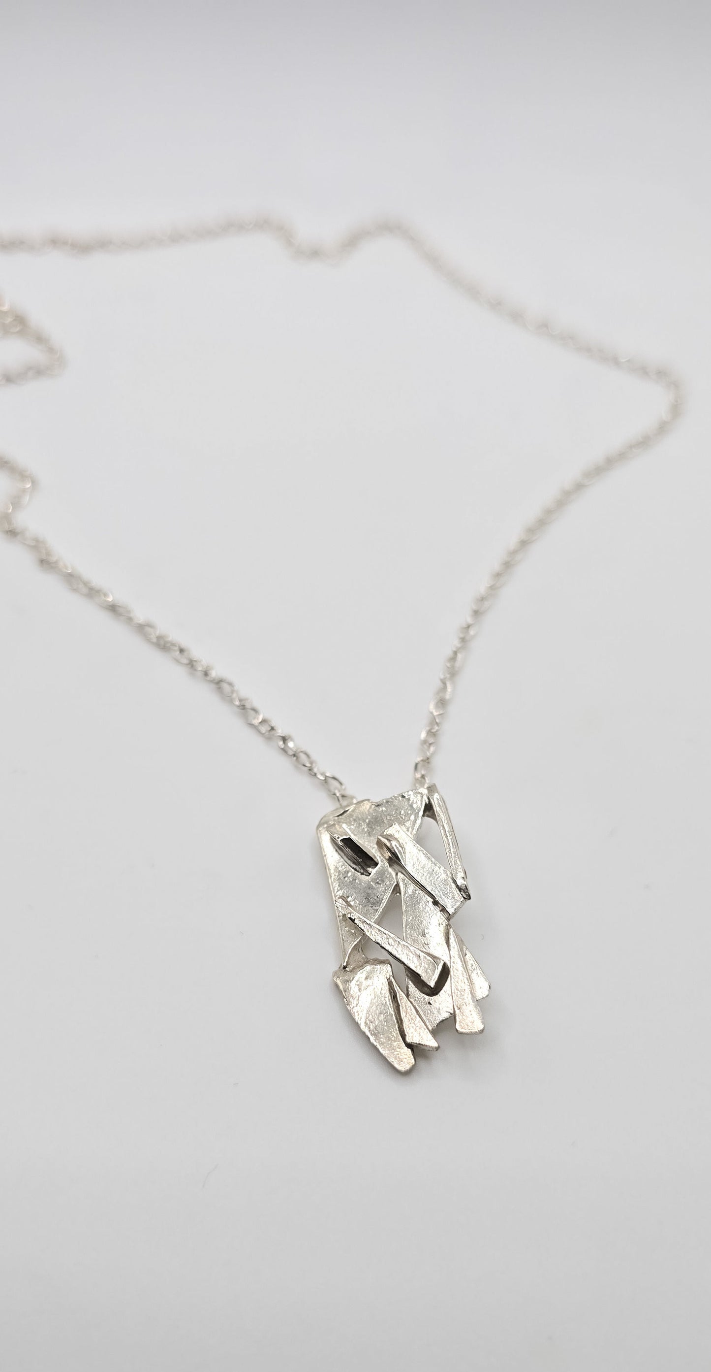 Made from shards of broken glass, this sterling silver pendant has a unique pattern. Comes on a 20" sterling chain. Made by Jill Melyssa