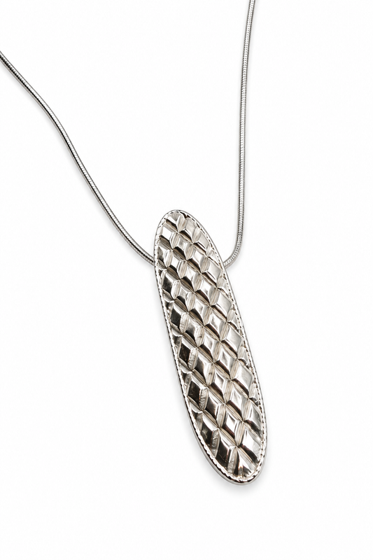 Close up of Jill Melyssa’s Quilted sterling silver necklace pendant, showing its dimensional geometric quilted pattern and reflective textured surface.