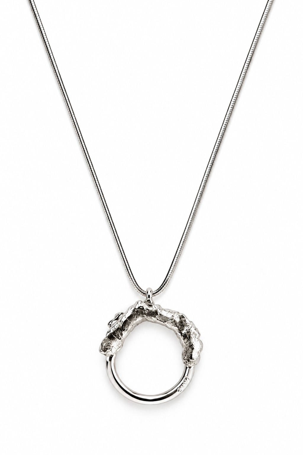 Close up of the Melted and Modern sterling silver necklace pendant, showing the contrast between its rugged molten texture and smooth polished circular form.