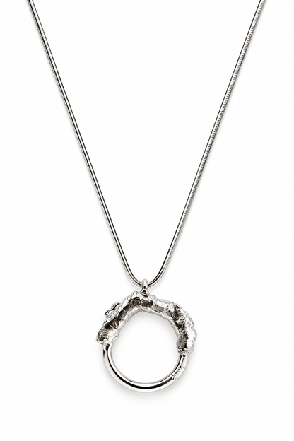 Close up of the Melted and Modern sterling silver necklace pendant, showing the contrast between its rugged molten texture and smooth polished circular form.