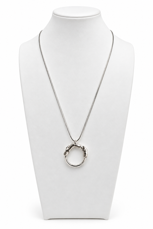 Melted and Modern sterling silver necklace displayed on a white jewelry bust, featuring a circular pendant with a textured molten silver upper form and smooth polished lower ring.
